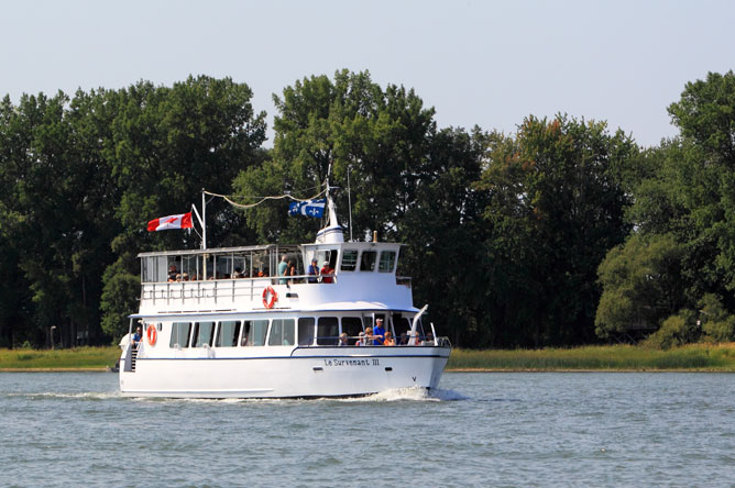 The 'Le Survenant III' cruise boat sails along a channel.
