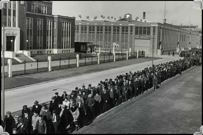 Photographie en noir et blanc montrant un très grand nombre de travailleurs devant l'usine.