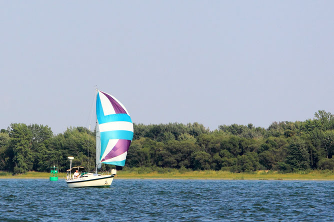 A sailboat in the St. Lawrence Seaway, near a green buoy