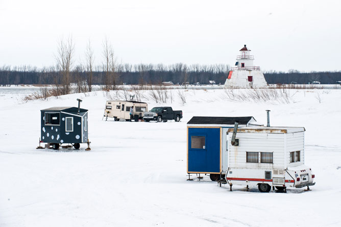 Fishing cabins on the ice in front of the lighthouse on Île du Moine
