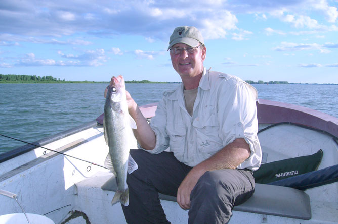 A fisherman in his boat, holding a good-sized Walleye.