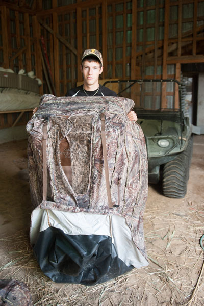 Young man presenting a blind where hunters lie on the ground to wait for ducks.
