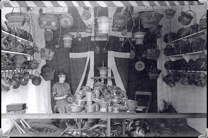 Une jeune femme confectionnant un panier dans un étal de souvenirs indiens vers 1935.