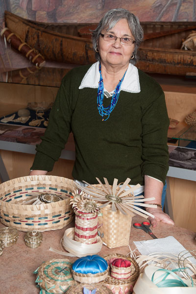 A woman presents the baskets she has woven.