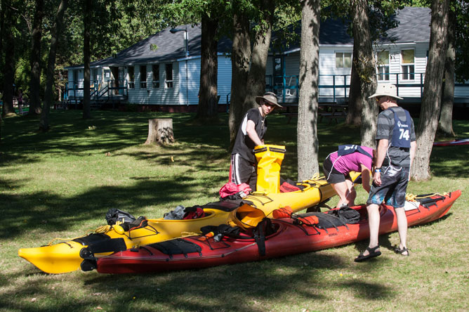 A woman and two men prepare to launch their two kayaks.