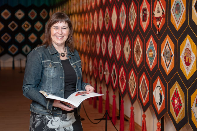 Michelle Bélanger, directrice du Musée des Abénakis, devant l'œuvre textile multicolore « Fibres du Monde ».