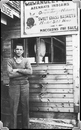 Un homme devant son comptoir de paniers et de souvenirs abénakis vers 1931