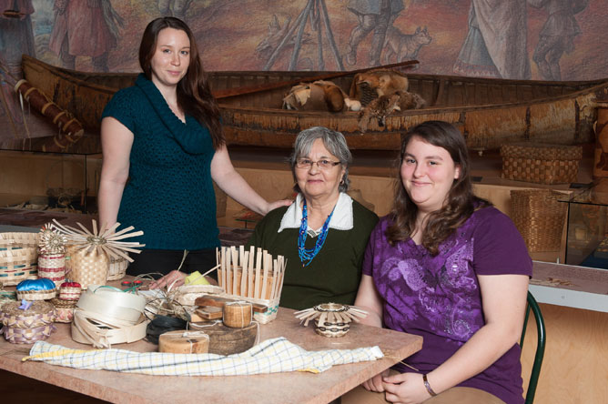 A woman and her two granddaughters present their basket weaving  materials and tools.