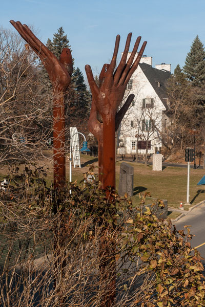 Sculptures dans le Parc portuaire de Trois-Rivières avec une vue rapprochée d'une sculpture avec des mains tendues vers le ciel